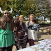 Three people in viking garb smiling in front of a table outside