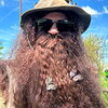 a man in a safari hat, sunglasses, and a fake beard with fake butterflies attached to it