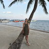 A person leaning on a palm tree next to the ocean