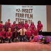A group of people in red shirts standing in front of a projector and next to an inflatable spider