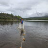 A man waving while holding a net and a rope of buoys out in water 