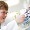 A smiling woman in a lab coat working with a piece of technology