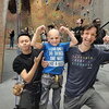 Two men flexing and smiling with a bald child in the middle also flexing