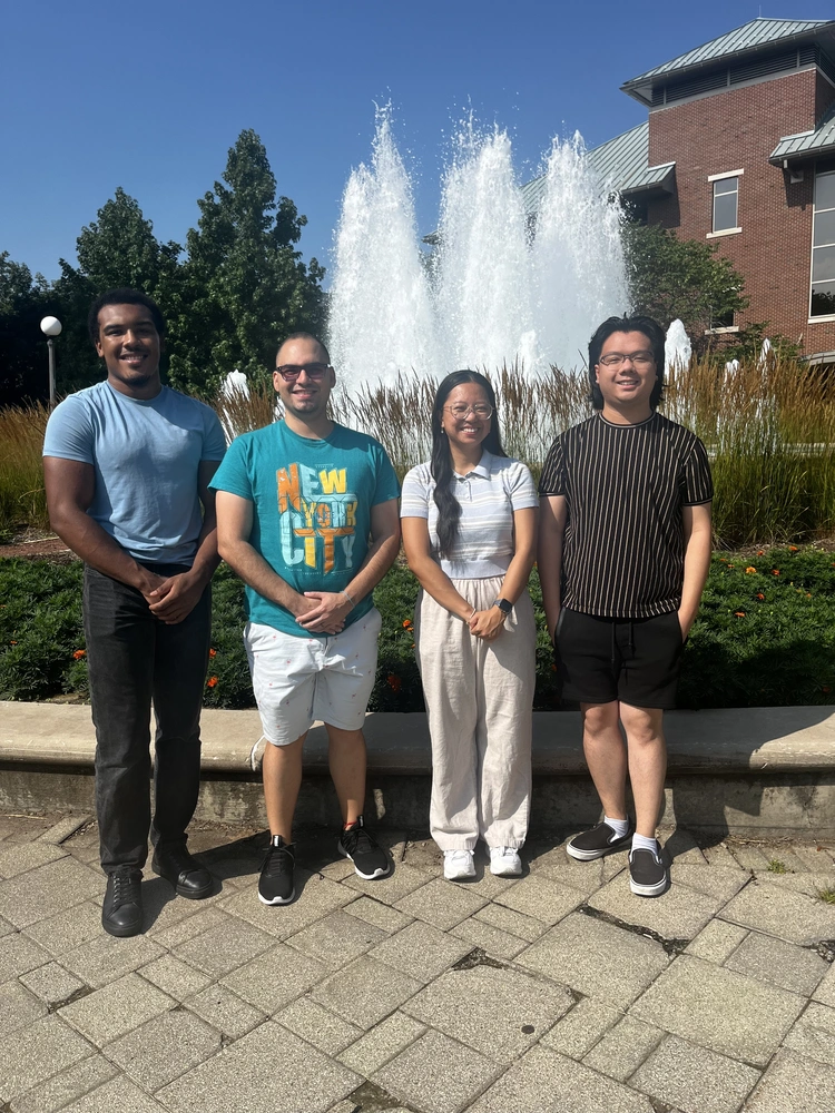 students posing next to one another in front of a fountain
