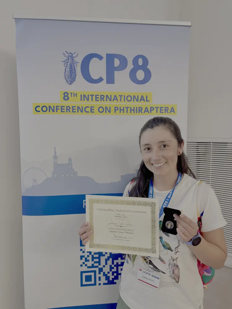 A photo of a student holding her award in front of a poster