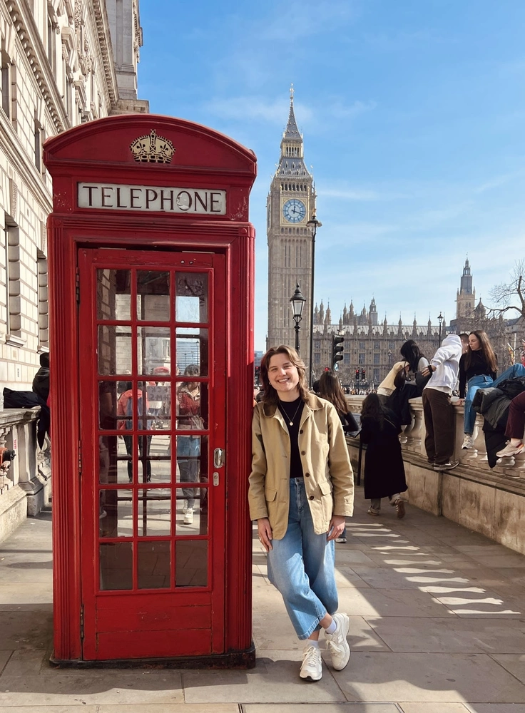 a woman standing next to a red telephone box