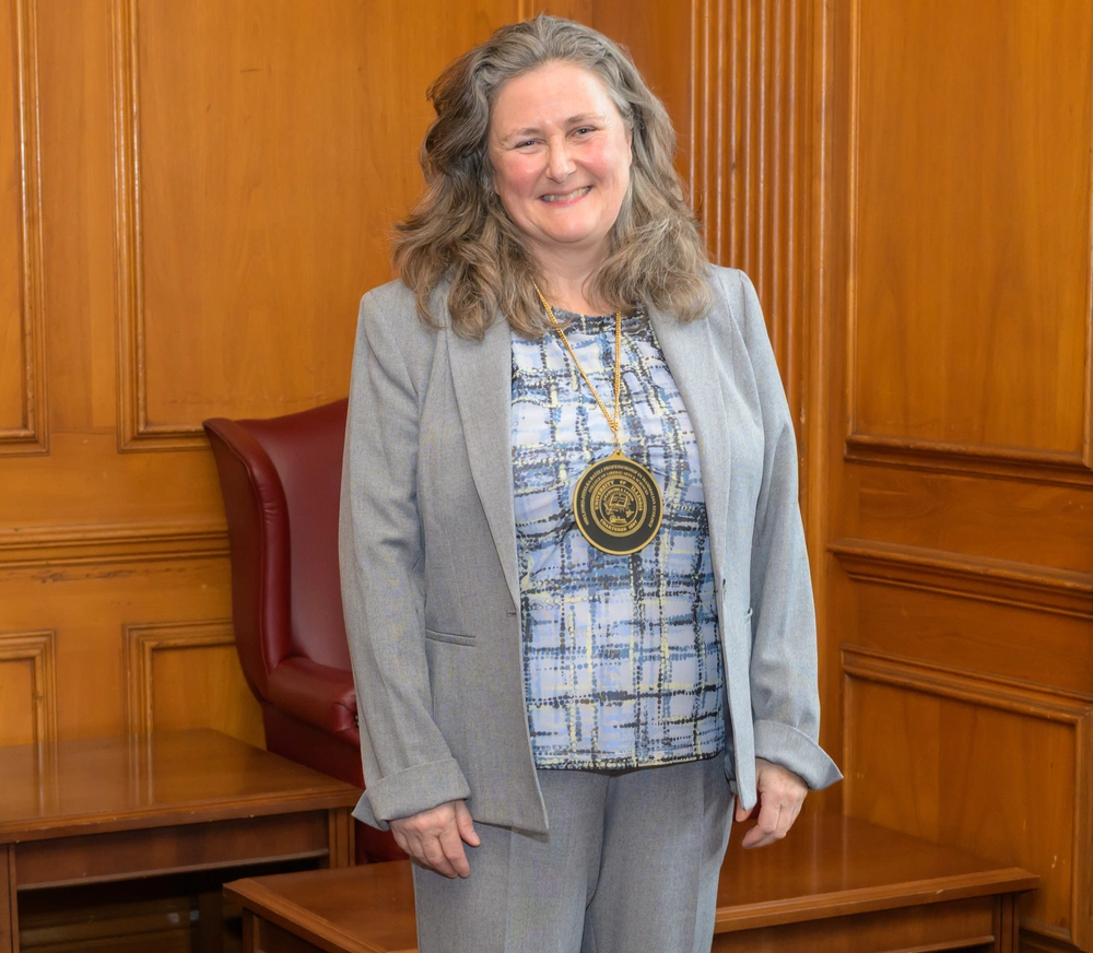 a smiling woman wearing a medallion