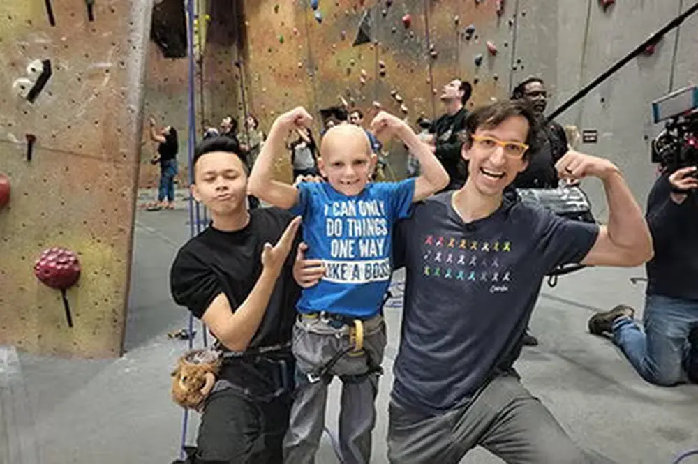 Two men flexing and smiling with a bald child in the middle also flexing
