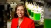 smiling woman in a lab with green fluid