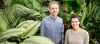 two smiling people in a green house