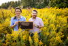 Two men standing in a field holding bees