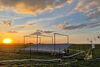 A photo of a field at sunset with a rain canopy over a part of it