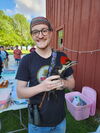 A photo of a man in a t-shirt and headband holding a bird at an outdoor event
