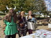 Three people in viking garb smiling in front of a table outside