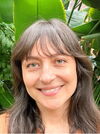 A smiling woman with brown hair in front a several plants