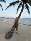 A person leaning on a palm tree next to the ocean
