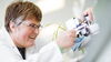 A smiling woman in a lab coat working with a piece of technology