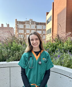 A photo of a young woman in green and orange scrubs