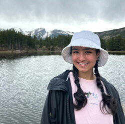 A photo of Simmi Rana standing next to a small lake