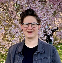 A photo of Elizabeth Bello standing in front of a pink flowering tree