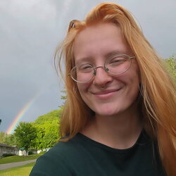 A photo of Naomi Cobb standing in front of a rainbow