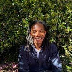 A photo of Derek McFarland sitting in front of a bush