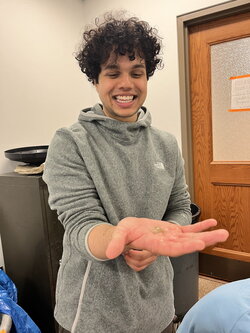 A photo of Shiram Bhat holding a small animal in a classroom