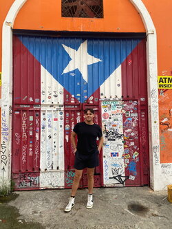 A photo of Abraham Morales standing in front of a building with a painted wall