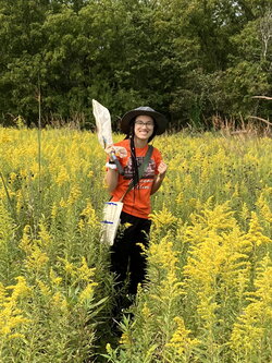 a photo of jenaya wilder standing out in a field with a bug catching net