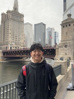 A photo of Junhe Zhang standing in front the Chicago River