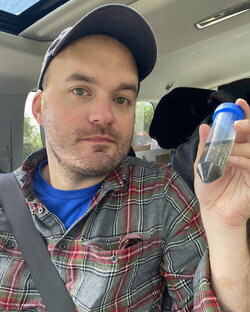 A photo of Lance Jones holding a vial in a car