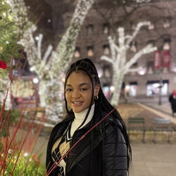 A photo of Nina Shearill standing in front of trees with white lights on them