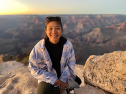 A photo of Sarah Chung sitting on rocks over looking a plateau