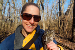 A photo of Tara Beveroth holding an owl in the woods