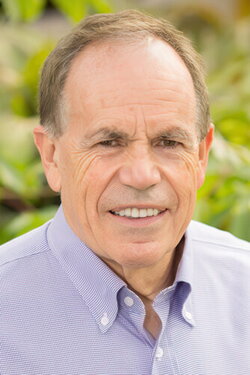 A man in a purple button up with a blurry plant background
