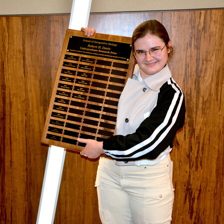 A person smiling and holding a plaque