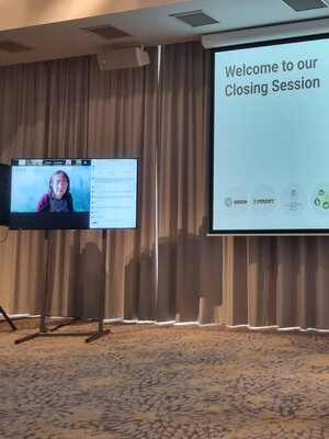 A person on a zoom call next to a large presentation on a projector