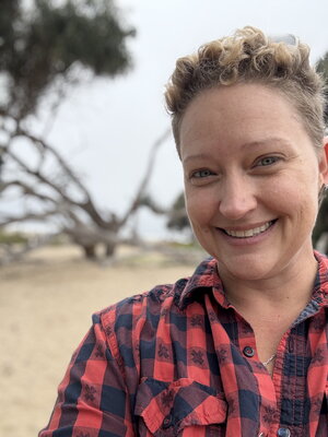 A woman in a plaid shirt smiling outside